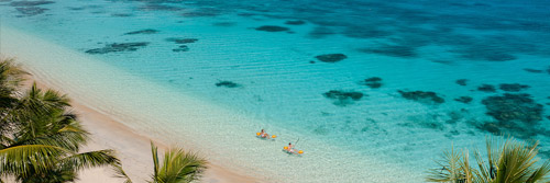 A birds-eye view of a guest kayaking along the shoreline at Kokomo Private Island.
