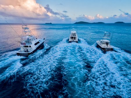 Three of Kokomo Island Fiji’s fishing boats cruising together into the distance, with two vessels featuring an upper level.