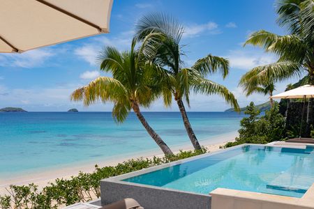A private beachfront infinity pool of a villa at Kokomo Island Fiji, with the beach extending out directly past it to the calm blue ocean.