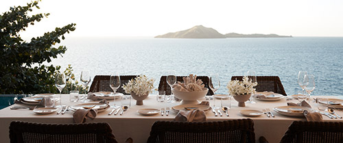 A dining setting overlooking the ocean at Kokomo Private Island Fiji.